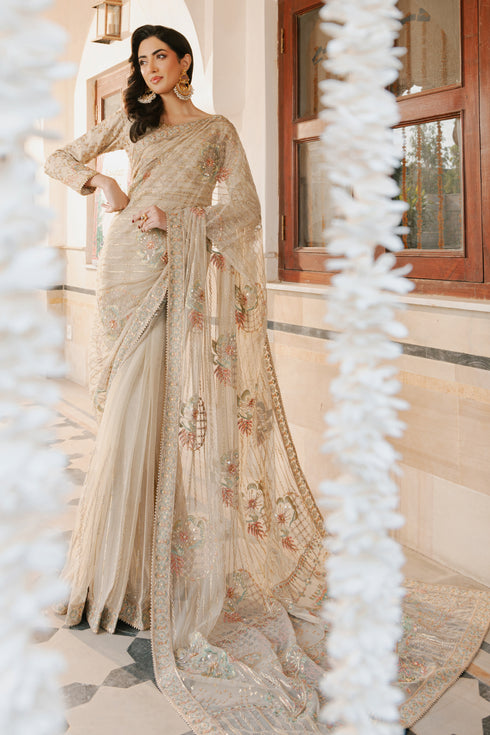 Model in full NAQSHI Ramish 3PC set: skin net saree, raw‑silk blouse with boat neck and fitted sleeves, floral‑embroidered pallu & raw‑silk petticoat